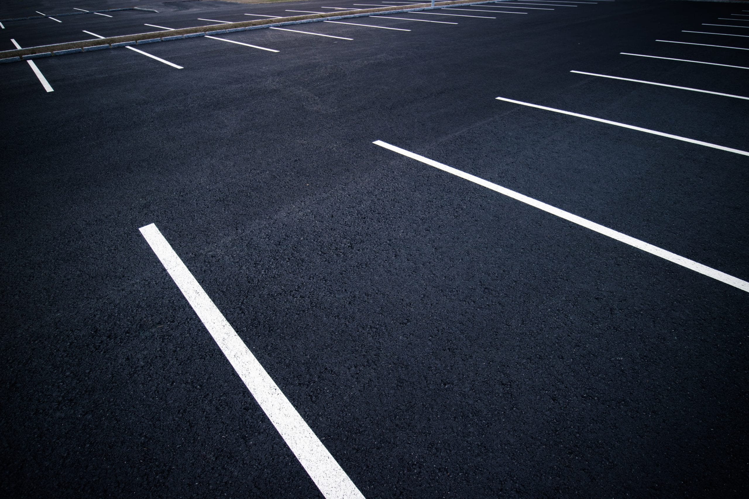 Empty parking lot with neatly marked white lines on dark asphalt.